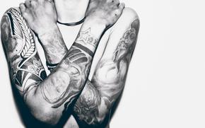 A man without a shirt, with his hands full of tattoos.