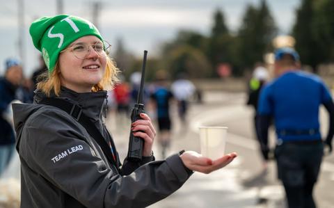 Photo Of U.S. Air Force Staff Sgt. Alison Riley hands water to half-marathon runners.