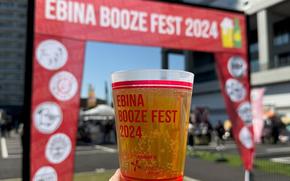 a cup of craft beer and a gate for the fest can be seen.
