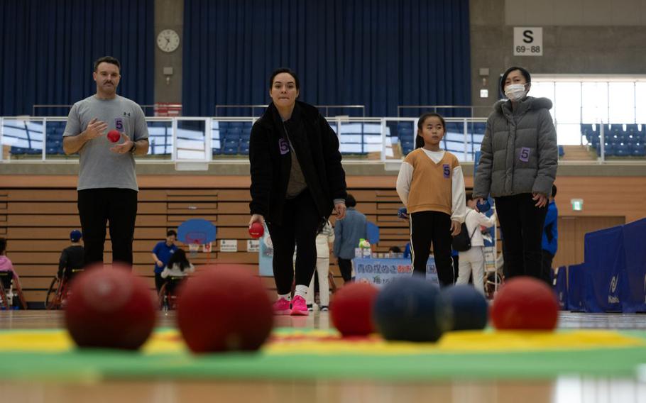 2nd Lt. Woolever throws a ball in a game of Boccia. three participants standing beside her.