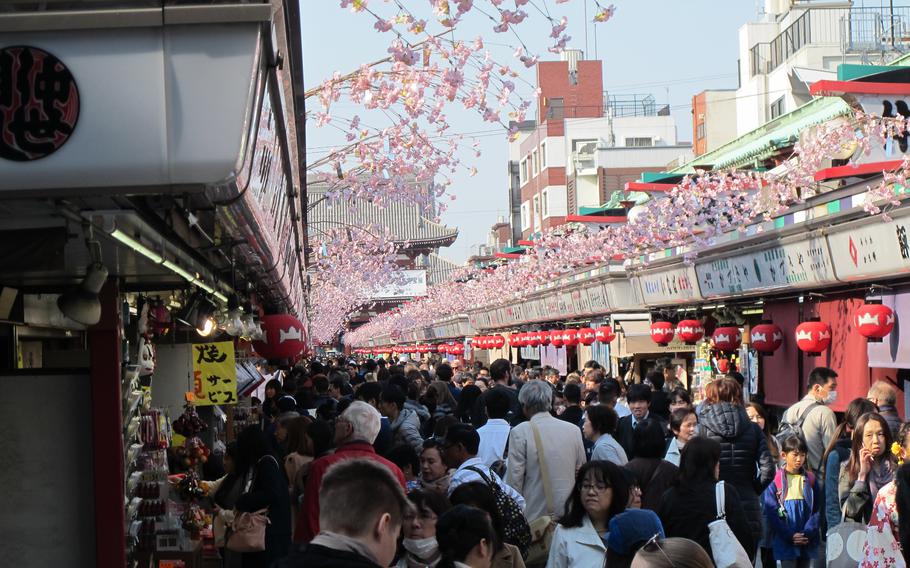 An approach to Sensoji Temple is lined with booths. Many visitors enjoy shopping.