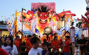 People enjoying Misawa Matsuri festival with illuminated, multi-color float shaped like demon.