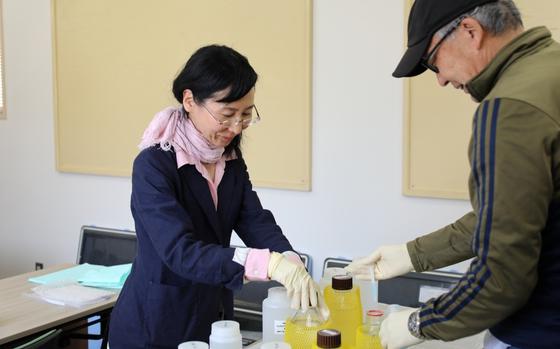 Photo Of Mikiko checks water samples with a male coworker inside a room.