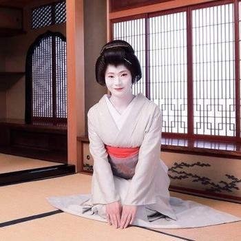 A geisha sitting on tatami mats.