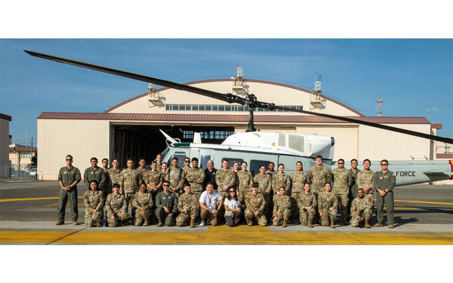 In sunny weather, about 40 participants of the National Hispanic Heritage Month orientation flight pose for a photo in front of a UH-1N Huey assigned to the 459th Airlift Squadron at Yokota Air Base, Japan, Oct. 2, 2024