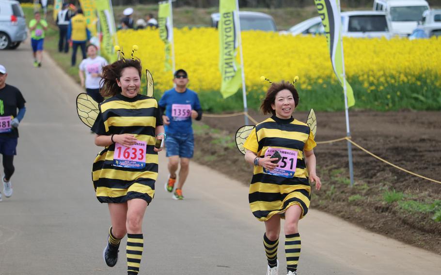Two women with bee’s costumes runnning on the road.