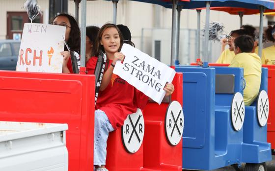 Photo Of Zama Middle High School students participate in a homecoming parade at Camp Zama, Japan, Oct. 10, 2024. One of the students carries a placard, saying “Zama Strong”.