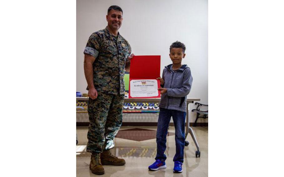 U.S. Marine Corps Col. Richard Rusnok, left, the commanding officer of Marine Corps Air Station Iwakuni, and a native of Pennsylvania, poses for a photo with a student from Matthew C. Perry PrimarySchool during an art awards presentation at MCAS Iwakuni, Japan, May 16, 2024. The air station compiled and displayed art from past winners of the monthly art awards competition for the 2023-2024 school year to recognize students and celebrate their completion of the school year.