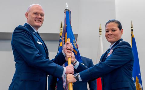 Photo Of U.S. Air Force Col. Jens Lyndrup, 515th Air Mobility Operations Wing commander, left, presents the guidon to Col. Cataleya Carlson, 515th Air Mobility Operations Group incoming commander.
