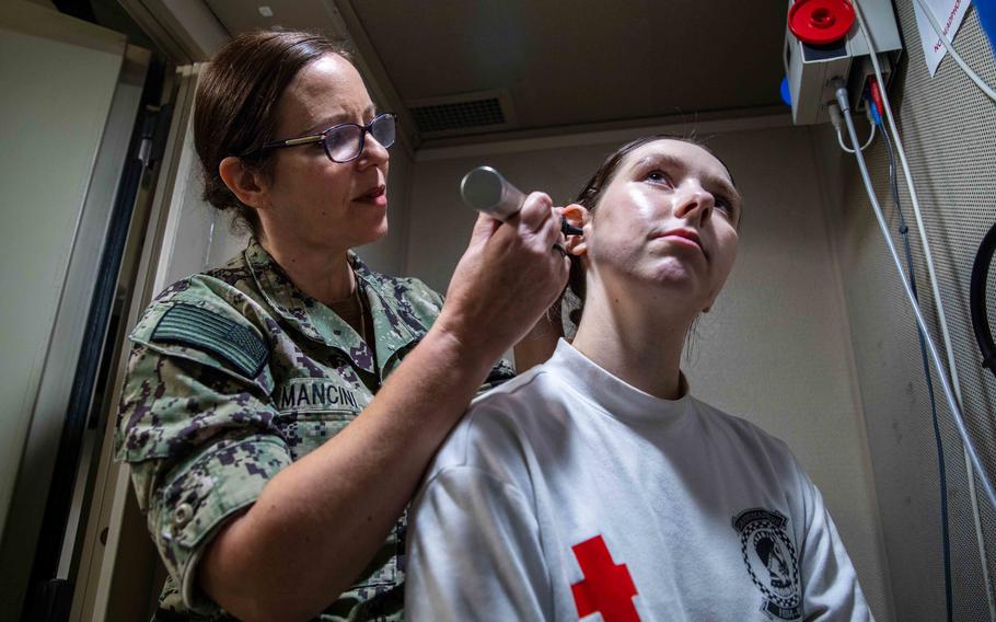 Lt. Cmdr. Mancini, assigned to Navy Medicine Readiness and Training Command Sigonella, performs an ear exam on Hospital Corpsman 3rd Class Maci Briscoe, assigned to Helicopter Maritime Strike Squadron (HSM) 46, aboard the Nimitz-class aircraft carrier USS George H. W. Bush.