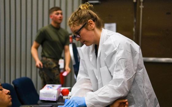Red Cross volunteer Mrs. Kirsten Moore prepares a service member for blood donation.