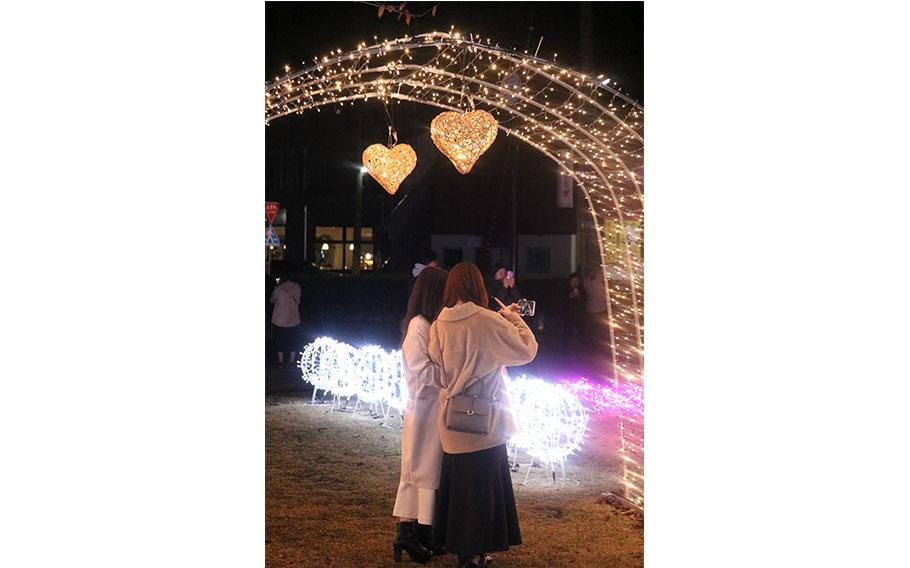 two people taking photos in front of the illuminations.