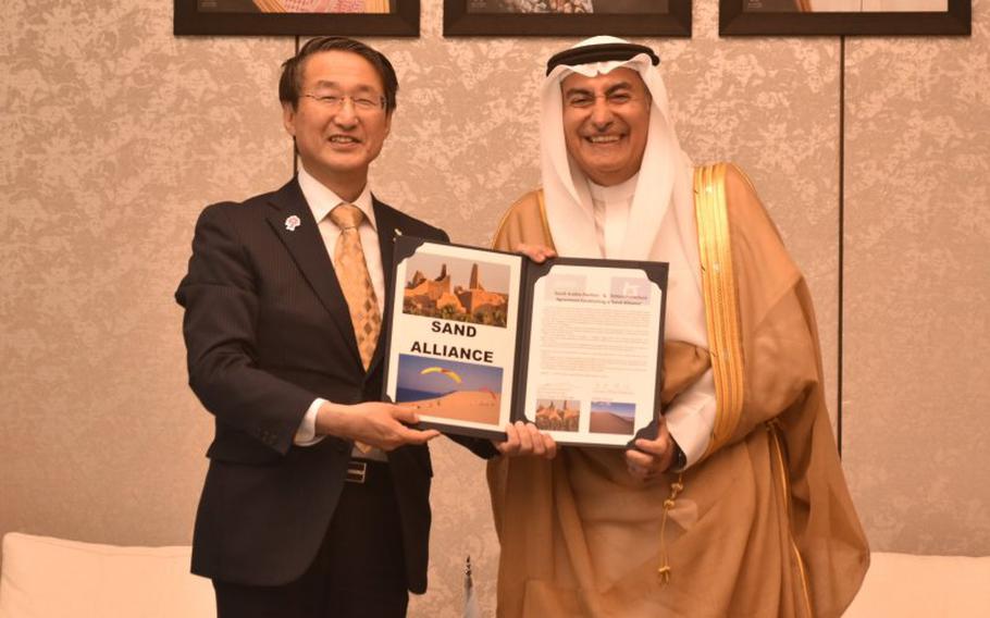 Two people pose for a photo with sand alliance.