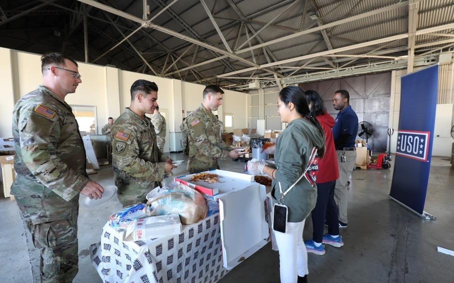 uso staff members serving pizza to soldiers.