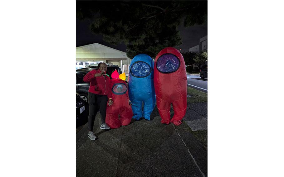 four people wear costumes in the parking lot.