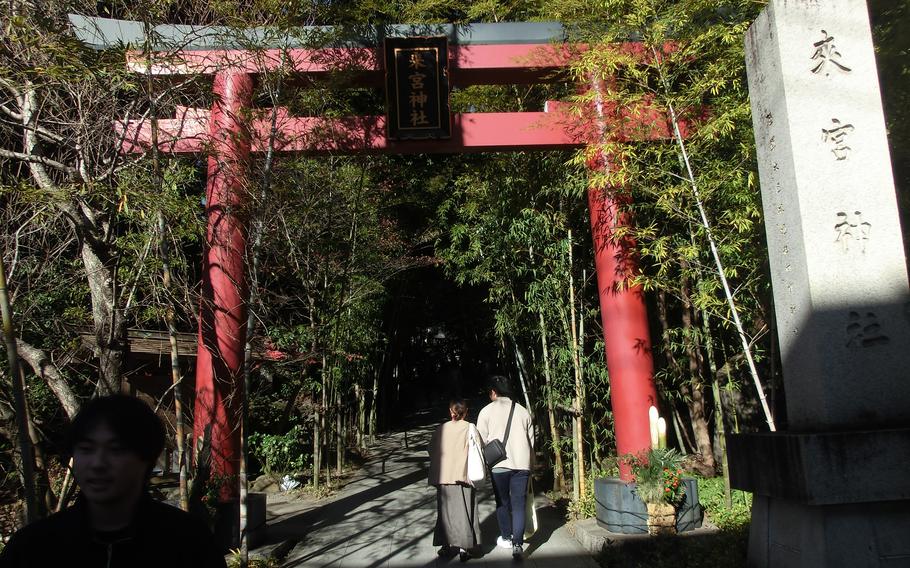 Two people walk under the torii gate at Kinomiya Shrine.