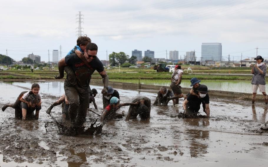 Participants join a muddy foot race in a rice field before a rice-planting event the Zama International Association hosted June 1 near Camp Zama. 