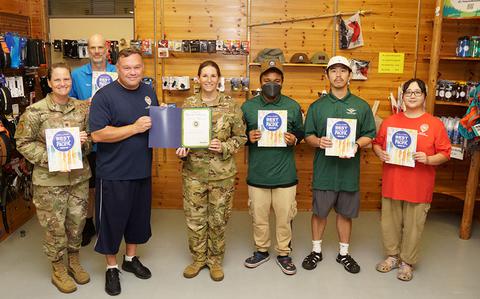 Photo Of Yokota Outdoor Rec staff group photo as Stars and Stripes Pacific Commander Lt. Col. Marci Hoffman presents award.