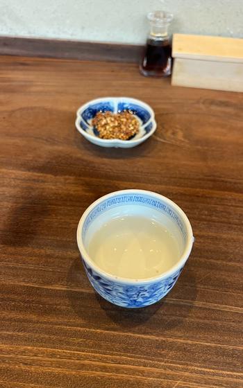 water in a tea cup and condiments in a plate on the table.