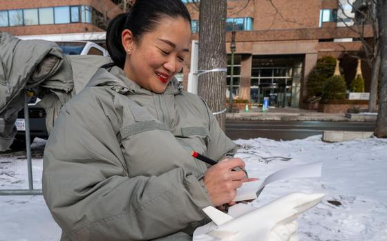 Photo Of 1st Class Caroline Lu with a coat on finishes a sketch as the team builds a snow sculpture during the 75th Annual Sapporo Snow Festival. 