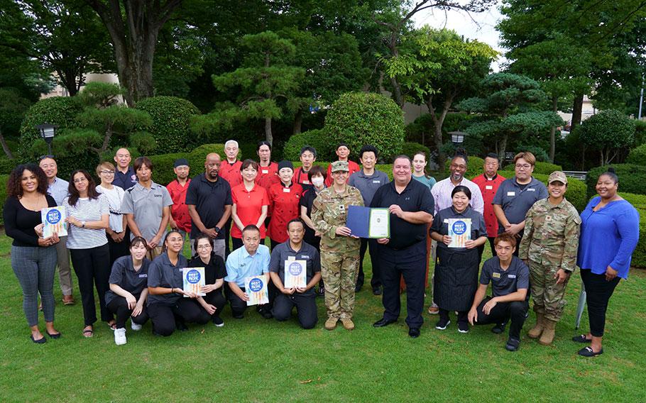 Yokota Enlisted Club staff group photo as Stars and Stripes Pacific Commander Lt. Col. Marci Hoffman presents award.