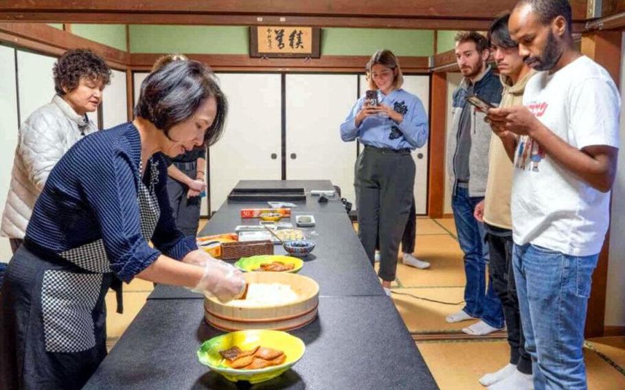 Participants taking photos of the instructor cooking in the cooking class.