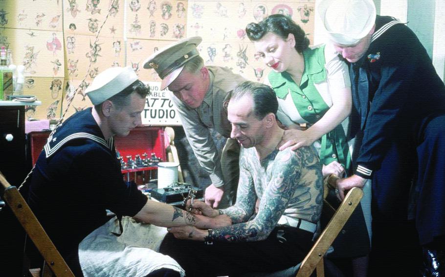 a person tattooing the other person’s arm. three people are seeing it.