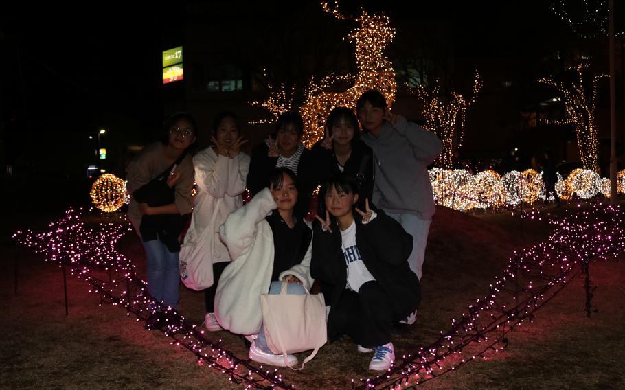 seven people pose in front of the illuminations.