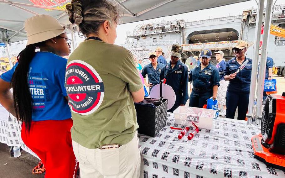 USS Tripoli service members were all smiles as they lined up to spin the wheel to win a prize, with Belinda Frampton and Beatrice Miles-Peterson enthusiastically cheering them on.