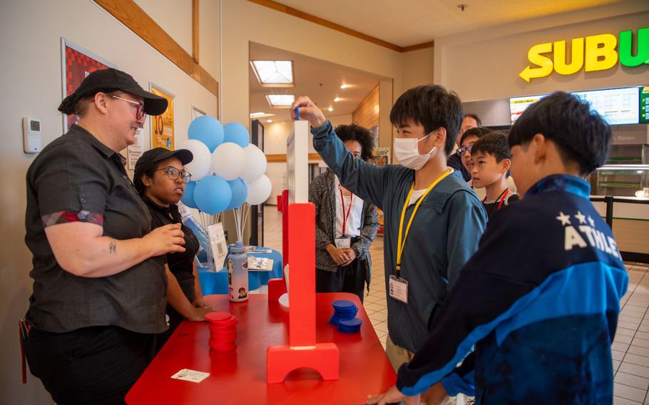 A Towada Middle School student plays Connect Four with Base Exchange food court members during a Junior English tour at Misawa Air Base, Japan, July 24, 2024. The goal of the tour was to help the youth of Towada, Oirase, and Misawa City improve their English skills while strengthening relationships between the base and the local community, highlighting the importance of educational and cultural exchanges in fostering strong partnerships. 