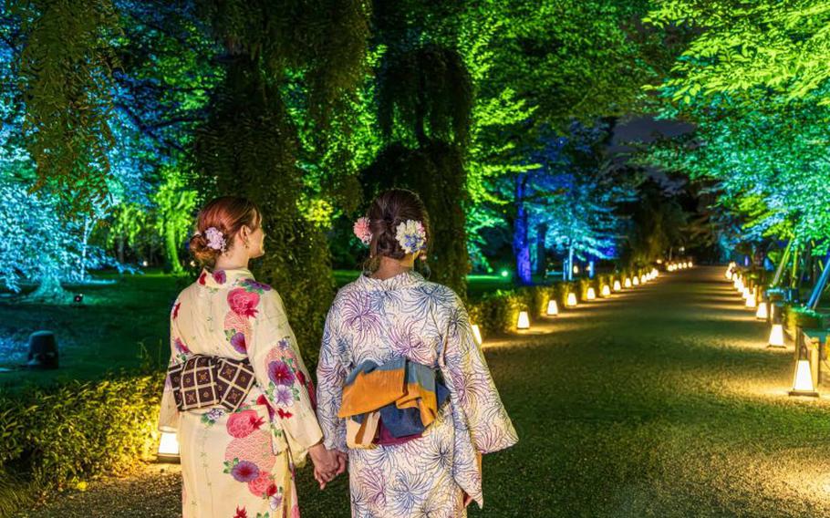 Two women walk on the illuminated street.