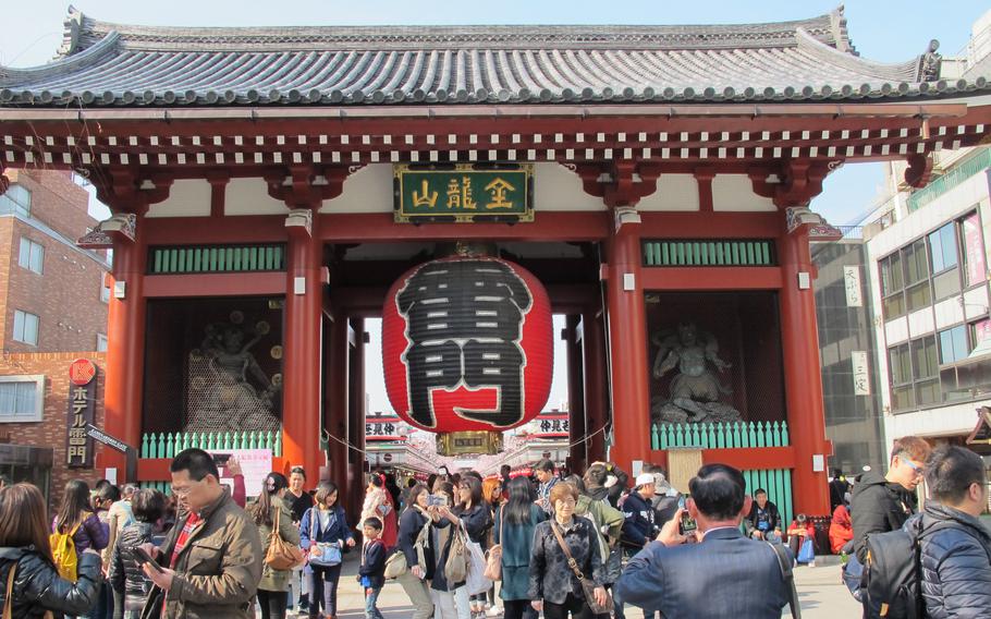 Many tourists take photos in front of the Kaminarimon gate.
