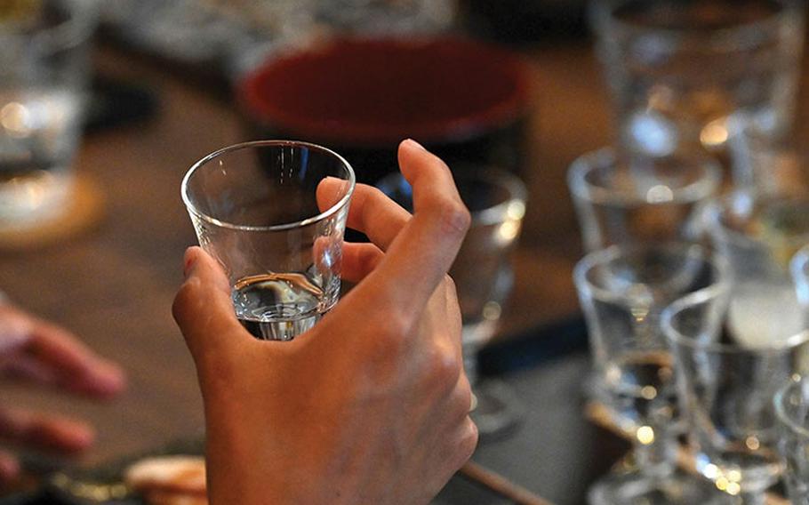 A person tests sake by tasting.