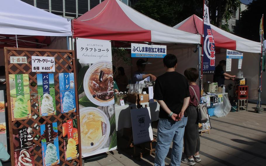 Two visitors are ordering beverages at one of the booths.