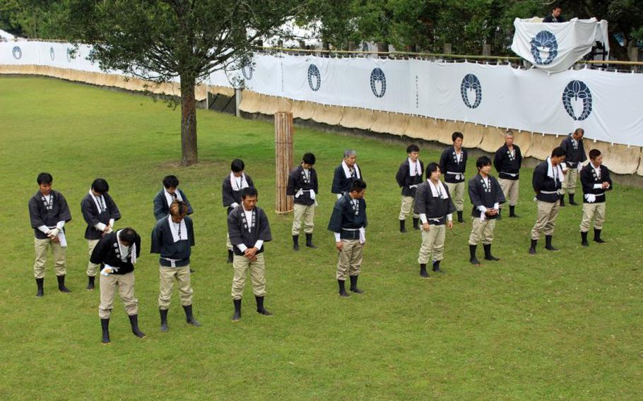 The 18 seko participating in the first day’s ceremony bow their heads to receive a blessing during the opening prayer.