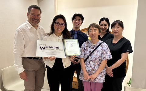 Photo Of Womble Gate American Dentistry staff group photo as Stars and Stripes Pacific Max Genao presents award.