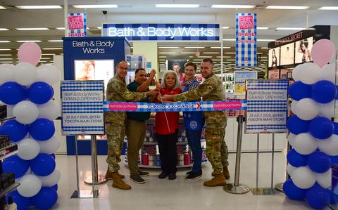 Photo Of five people pose for a photo in front of the ribbon.