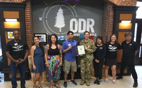 Photo Of Misawa Outdoor Rec staff group photo as Stars and Stripes Pacific Commander Lt. Col. Marci Hoffman presents award.