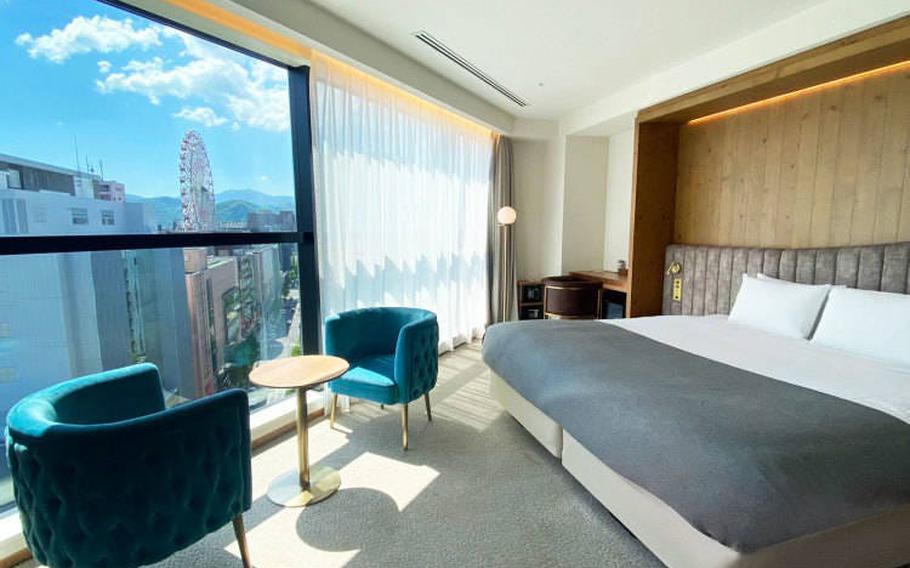 Deluxe King room offers a panoramic view of the Sapporo cityscape from the room-length window.