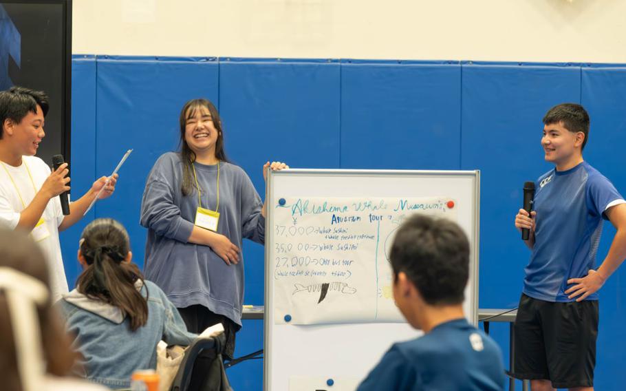 Three students from Yokota High School and local Japanese high schools present their product idea by using a whiteboard.