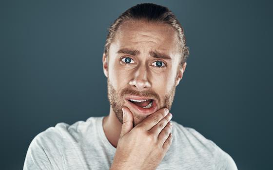 Photo Of Oops! Shocked young man looking at camera and making a face while standing against grey background   