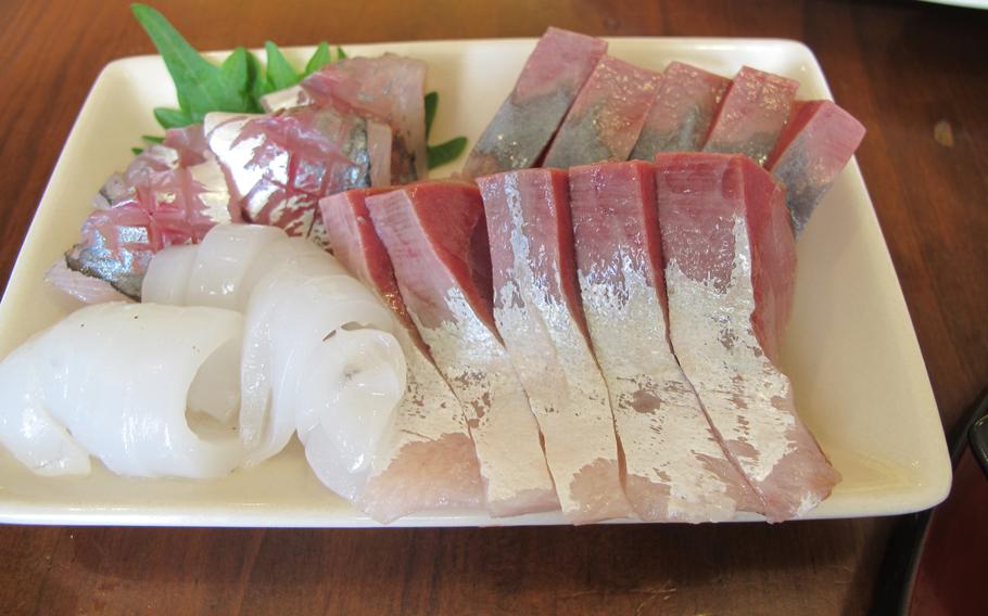 sashimi of yellowtail, squid and horse mackerel on a plate.