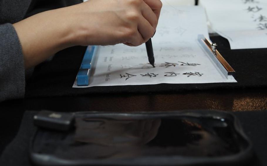 A person writing Chinese characters with a writing brush.