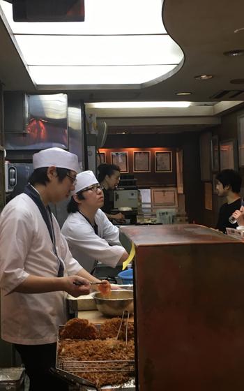 The interior of the restaurant. Staff members are cooking.