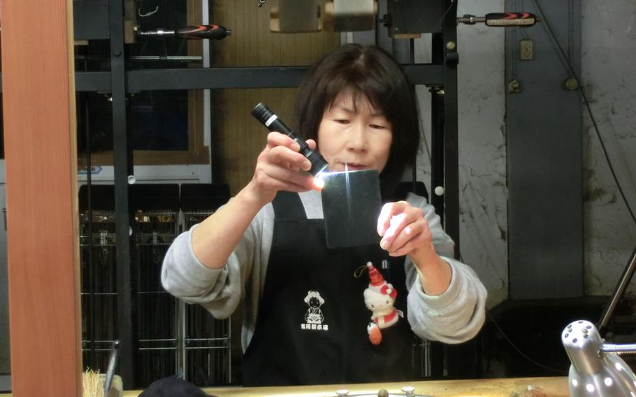 A staff member demonstrates the silk reeling.