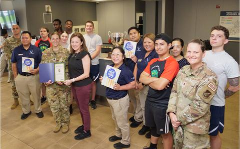 Photo Of Samurai Fitness Center staff group photo as Stars and Stripes Pacific Commander Lt. Col. Marci Hoffman presents award.