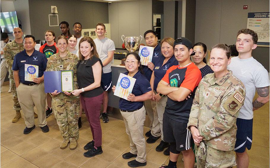 Samurai Fitness Center staff group photo as Stars and Stripes Pacific Commander Lt. Col. Marci Hoffman presents award.