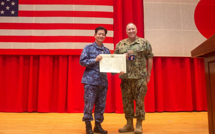 YOKOSUKA, Japan (Oct. 21, 2021) - Rear Adm. Will Pennington receives an award from Vice Adm. SAITO Akira, commander of Japan Maritime Self-Defense Force (JMSDF) Fleet Escort Force during the change of command ceremony for Commander, Task Force (CTF) 70 in the Benny Decker Theater on Yokosuka Naval Base, Oct. 21. (U.S. Navy photo by Mass Communication Specialist 3rd Class Askia Collins)