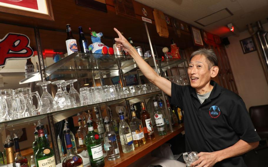 Takeshi Kusunoki, a bartender at the Kure Harbor Club, points to plaques that military units have presented to the club for its support at Kure Pier 6, Japan, Sept. 5, 2024.