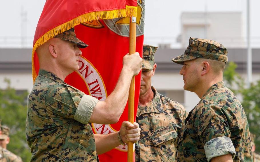 U.S. Marine Corps Col. Kenneth Rossman, left, oncoming commanding officer, Marine Corps Air Station Iwakuni, takes the station colors from Col. Richard Rusnok, right, outgoing commanding officer, MCAS Iwakuni, during a change of command ceremony at MCAS Iwakuni, Japan.